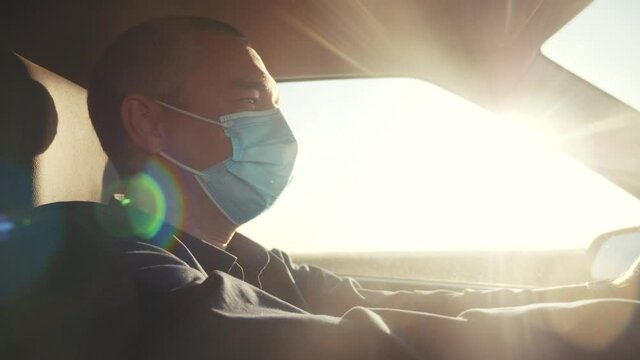 worker driver wearing a medical mask drives a car during the coronavirus period. delivery during the pandemic covid 19 parcel concept. man wearing a mask taxi driver protection against coronavirus