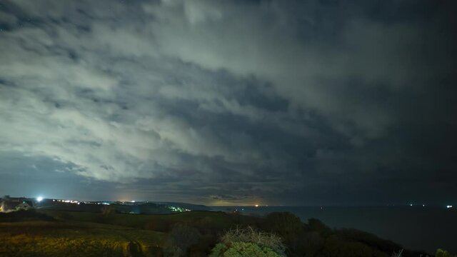Time lapse of clouds & stars over countryside landscape & ocean at night
