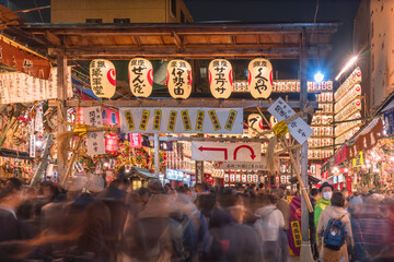 Crowd passing through a gate of Tori-no-Ichi Fair decorated with luminous lanterns in Ootori shrine...