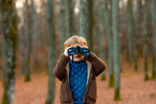 Kid Looking Through Binoculars In Forest. Child Playing Outdoors. Kids Travel And Adventure Concept.