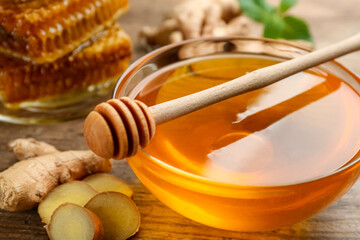 Honey in bowl and ginger on wooden table, closeup. Natural cold remedies