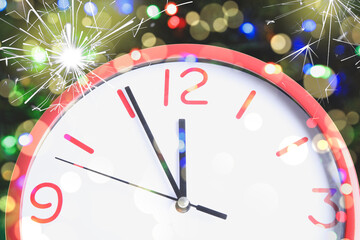 Fototapeta na wymiar Clock showing five minutes till midnight with sparklers, closeup with bokeh effect. New Year countdown