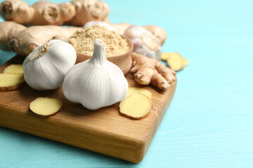 Ginger and fresh garlic on light blue wooden table, space for text. Natural cold remedies