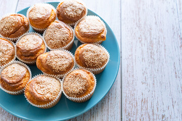 Close up top view on fresh homemade corn pone muffins in blue plate on wooden rustic table background with copy space