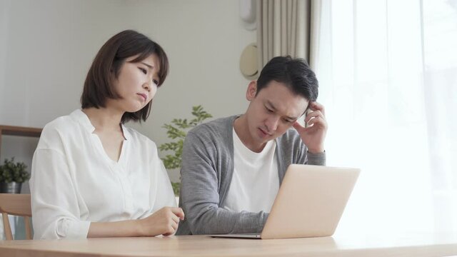 リビングでパソコンを見る夫婦・カップル