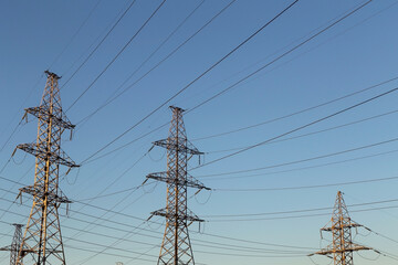 Electric powerlines. High voltage power lines, pylons on blue sky background
