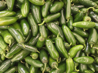 High angle close-up view of fresh green jalapeño peppers displayed for sale at a grocery market