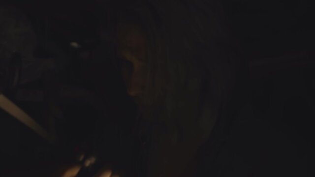 Woman with flashlight in dark shelter talking on walkie-talkie