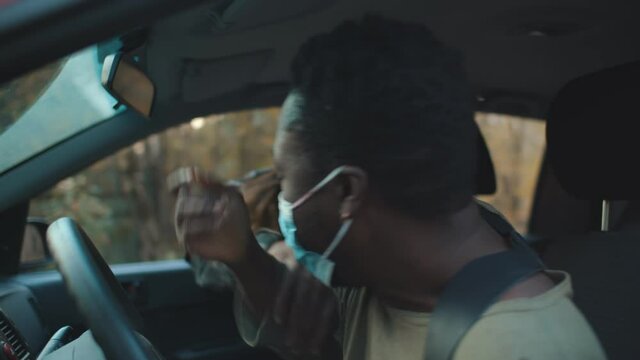 Creepy zombie man attacking african guy driving car on road