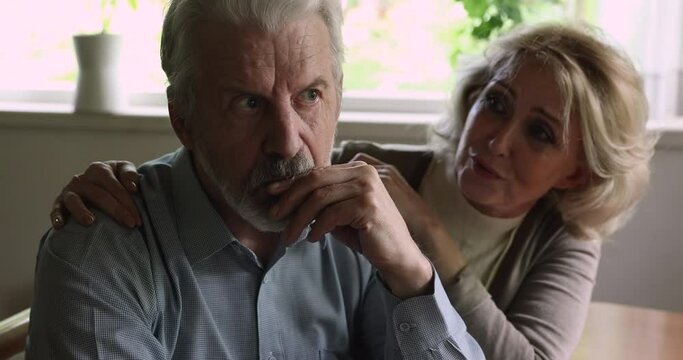 Elderly man sit with wife indoor feels upset, loving woman put hand on shoulders hugs him comforting, express empathy, close up. Crisis, impotence, potency health problems, incurable disease concept