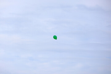 空に飛び立つ緑色の風船