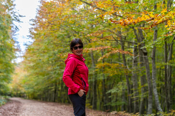 young woman walking among beech trees in autumn