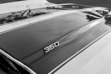 Fototapeta na wymiar Black and white hood of a classic muscle car with a 350 engine