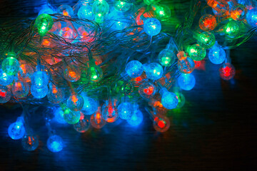 Beautiful Christmas garland glowing in the dark. Led holiday light bulbs with tangled wires.