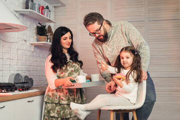 a woman treats her daughter and husband with tea and donuts