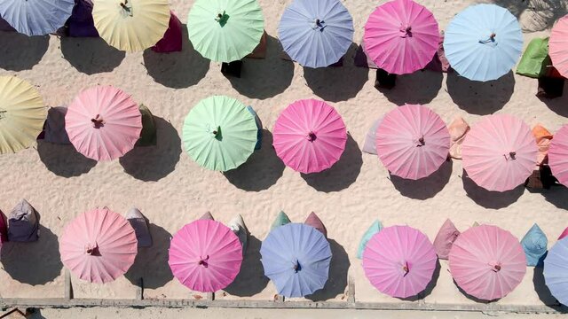 Colorful umbrellas on golden beach during sunny day.Aerial top down view.Gili Island,Indonesia.