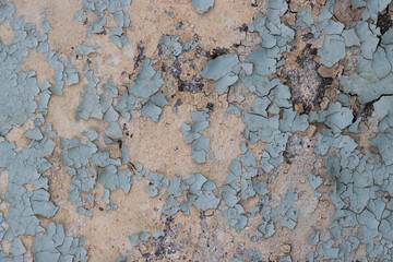 Peeling paint on the wall. Old concrete wall with cracked flaking paint. Weathered rough painted surface with patterns of cracks and peeling. Grunge texture for background and design. High resolution.