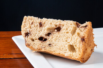Panettone traditional Italian dessert for Christmas. Slices cut with black background.
