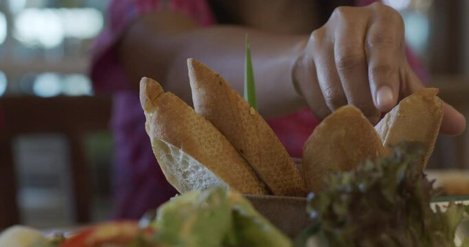 Close up woman and child pick up the garlic breads in the wooden bowl in restaurant. Healthy eating and diet concept.