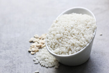 A porcelain bowl with white rice and oatmeal is on the kitchen table.