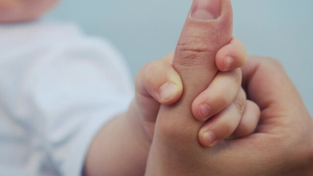 baby newborn holding a mom hand. kid dream concept. close-up baby hand grabs finger of mother hand. newborn baby and mom hands. mother taking care of her kid son happy family dream of health fun