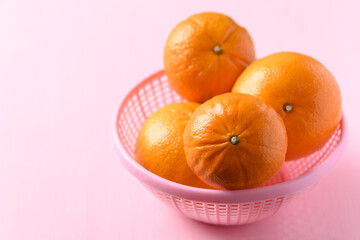 Fresh Honey Murcott orange fruit in a basket on pink background