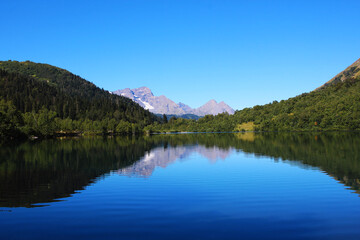 Fototapeta na wymiar A clear blue lake with a special ecology located in the mountains and surrounded by forest. Caucasus, lake Kardyvach