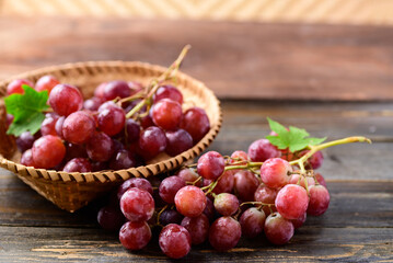 Fresh red grapes fruit in a basket on wooden background