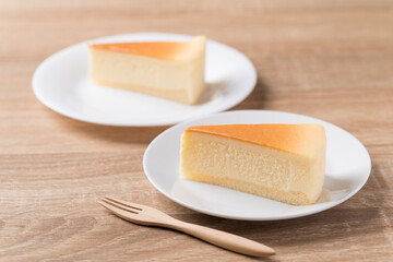 Slice of vanilla cheesecake on white plate with fork