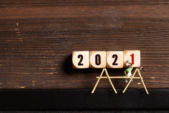 little painter figures and message 2021 on wooden cubes in front of wooden background