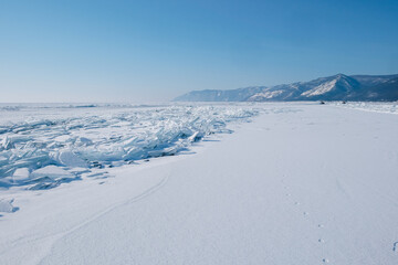 Snow-covered landscape of the clean lake Baikal. Fragments, blocks of transparent ice. Winter landscape for background, banners.