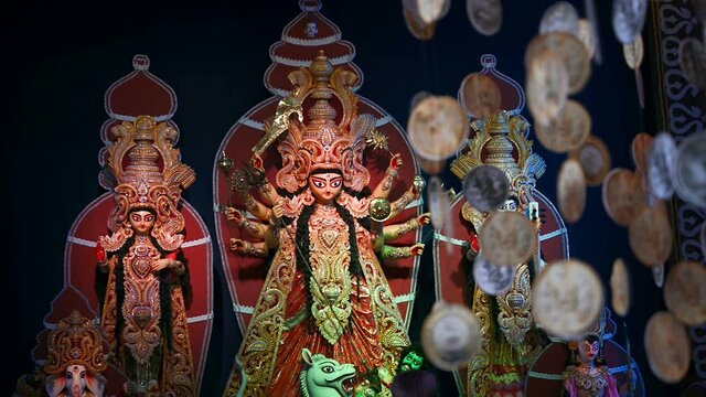 Decorated Durga Puja pandal with Durga idol, Out of focus hanging coins , Durga Puja festival at night. Slow mo HD footage shot under colored light.