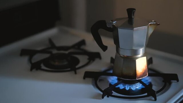 moka pot on gas burner of old stove lights in slow motion in morning sunlight