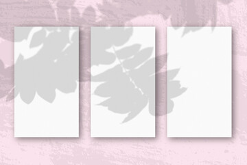 3 vertical sheets of textured white paper on soft pink table background. Mockup overlay with the plant shadows. Natural light casts shadows from a Rowan branch. Horizontal orientation