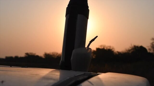 termo y mate bebida tipica tradicional argetina cordoba sobre techo de un auto en atardecer en campo agronomia cosechado en invierno