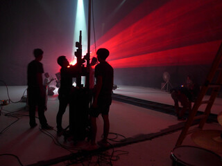 Blurry image and out of focus : Behind the scenes of video shooting production crew team silhouette and camera equipment in studio, Red laser light beam