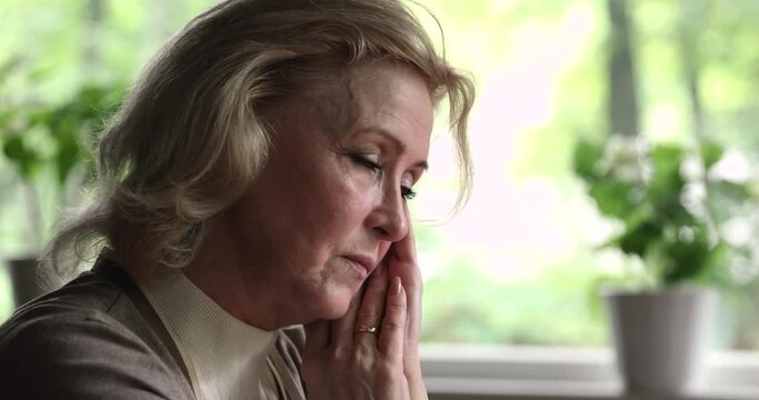 Close up old woman sit indoor lost in sad thoughts grieving feels unhappy, widow mourns her husband, goes through divorce, experiences difficult life period, granny suffer from grief, disease concept