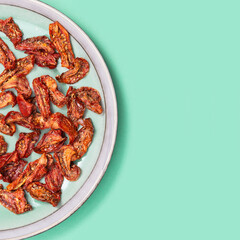 Sun dried tomatoes slices with Italian herbs and spices on blue colored background. Homemade dehydrated vegetable.