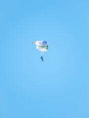 one parachutist floats slowly at low altitude on the background of clear sky