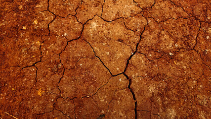 Textured background of cracked dry brown red earth. Cracked loose soil