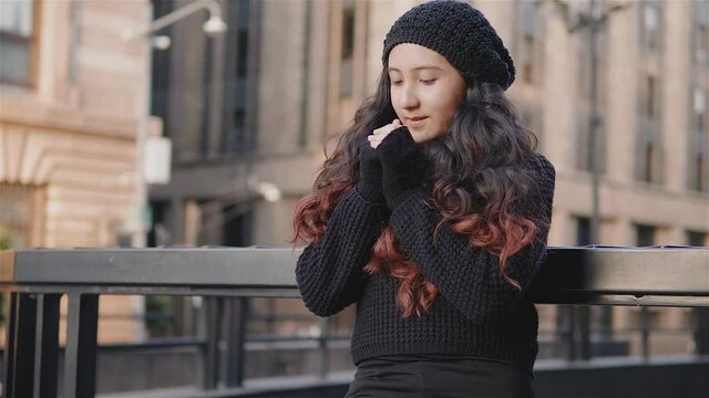 Vista de una ni&ntilde;a adolescente por las calles de la Ciudad de M&eacute;xico con ropa de abrigo en una tarde de oto&ntilde;o, ni&ntilde;a se frota las manos porque tiene frio, imagen urbana con una chica recargada