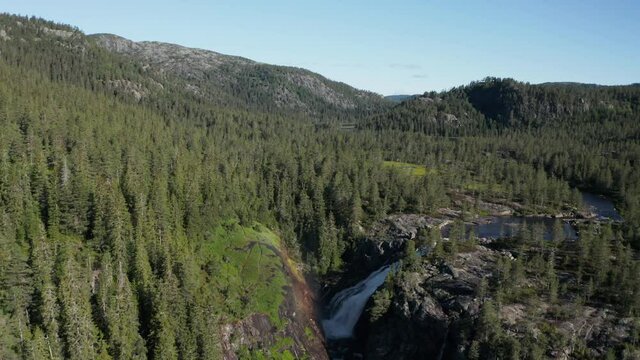 Flying over evergreen forest toward famous Rjukanfossen Waterfall, Norway