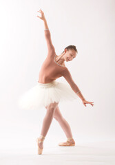 Fototapeta premium Young woman ballet dancer on pointe in the studio.
