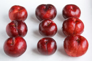 Row of Fresh juicy red plums isolated on white