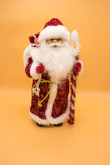 Ceramic statuette of Santa Claus in a red coat holding a staff isolated on yellow background