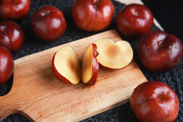 Fototapeta na wymiar Fresh juicy red plums on cutting board. Sliced plum by knife