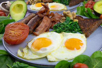 Fried eggs and bacon with a serve of spinach mushrooms and toast