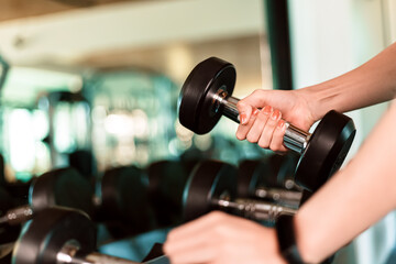 women hands lifting dumbbells workouts with dumbbells in a gym. Sport women at fitness gym.