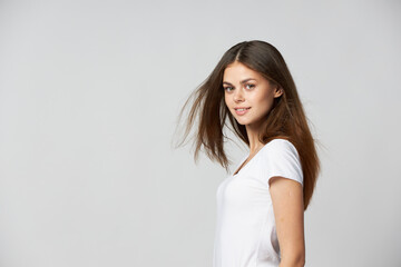 Fototapeta premium Beautiful woman in a white T-shirt with loose hair side view smile