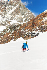 Full length image of a snowboarding standing in a snow, high mountain background. Vertical view.